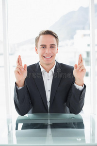 微笑的商人在办公桌前交叉手指