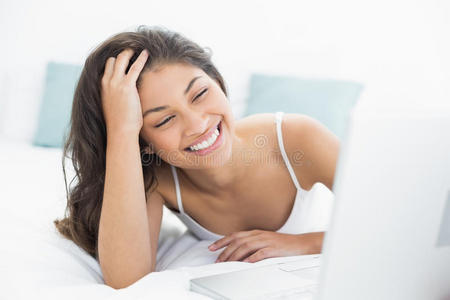 在床上使用笔记本电脑的快乐休闲女性