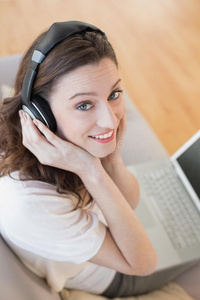 休闲的女人在家里欣赏音乐时用笔记本电脑