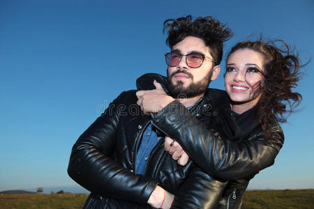 微笑的女人拥抱着她的爱人,两个人都看向别处照片