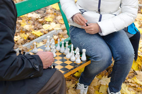 老人和女人在公园的木凳上围棋图片