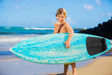 海滩上带冲浪板的快乐小男孩