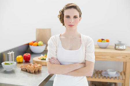 安静严肃的女人双臂交叉站在厨房里
