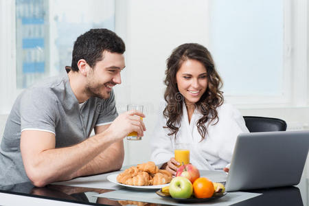 一对漂亮的夫妇用笔记本电脑吃早餐