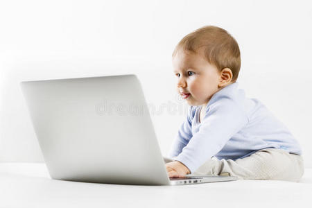 可爱的小男孩好奇地看着笔记本电脑屏幕。