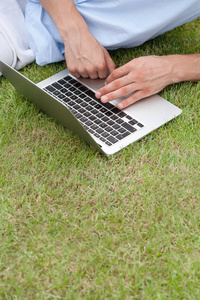 在草地上使用笔记本电脑的人