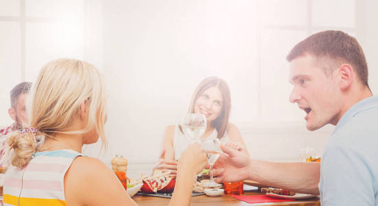 人和金发女人在餐桌旁，为朋友聚会