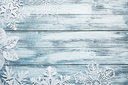 漂亮的纸雪花飘落在木制的背景图片