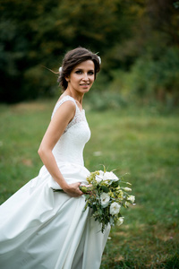 用一束美丽的鲜花的美丽的新娘穿着婚纱肖像