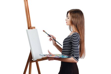 可爱漂亮的女孩艺术家画一幅画在画布上画架上。文本的空间。工作室白色背景孤立