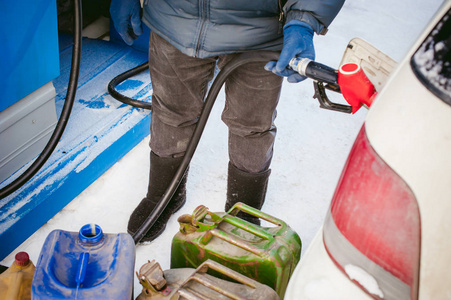 成年男子在冬天用燃料加油站填充一辆车