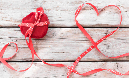礼品盒心形木背景上的红色蝴蝶结丝带情人节