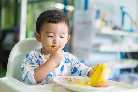 亚洲孩子脸上吃奶油生日蛋糕