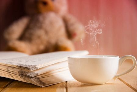 咖啡杯和本书侧重于模糊背景的泰迪熊