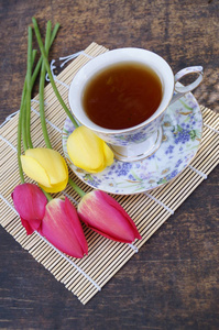 清茶一杯，郁金香花，木制的背景上。春天作文