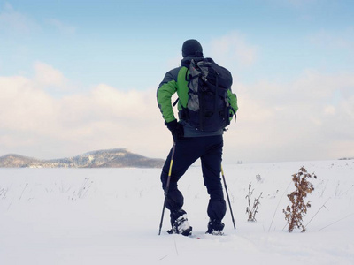 雪鞋走在雪提起的男人。徒步旅行者在粉雪的雪鞋