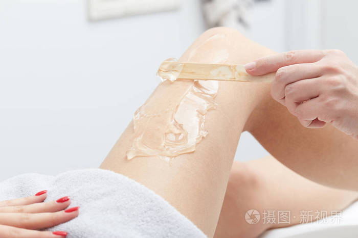 美容师给脱毛蜡治疗到女人的大腿