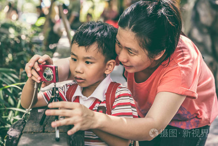 幸福的家庭。教学男孩在户外拍摄的女人。复古色调