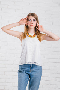 牛仔服饰年轻漂亮性感时尚性感女人假扮白墙背景上穿着时髦风格牛仔裤