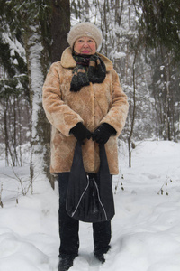 高级妇女皮大衣和帽子的肖像站在寒冷的冬天雪覆盖森林, 关闭