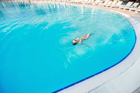 女人在蓝色的海水游泳池游泳