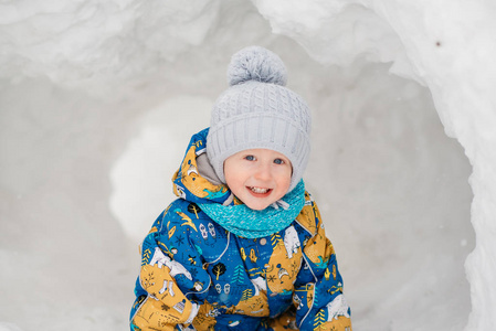 可爱的小男孩孩子在外面玩，他在堆雪挖在冬天里的雪屋堡隧道