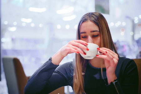 年轻女子在一件黑色的连衣裙，手里拿着一杯