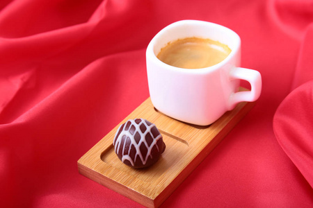 咖啡与巧克力果仁糖红色背景上的白色杯