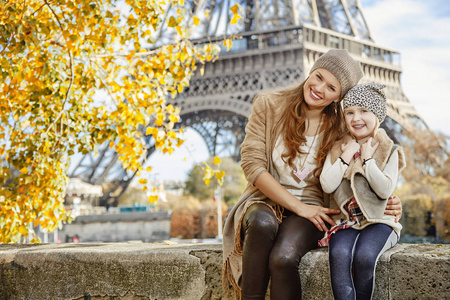 母亲和孩子的游客坐在巴黎的护墙上