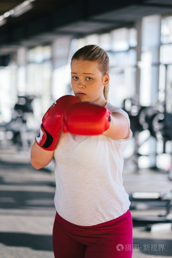 年轻的危险拳击手女孩训练拳击和投掷攻击性拳打在健身房战斗