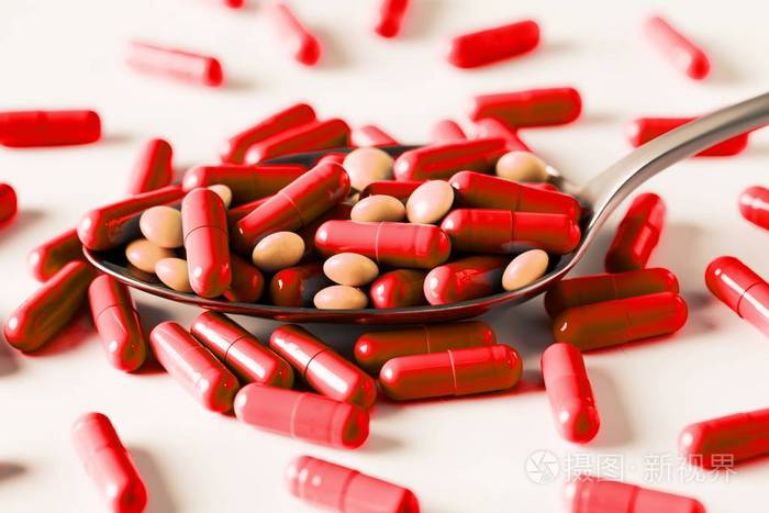 红色胶囊和汤匙里的橙色药丸