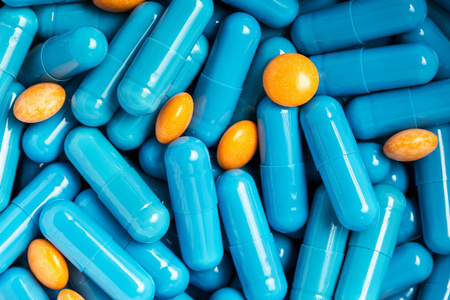 蓝色的医疗药片和胶囊图案平躺,顶视图蓝色背景上有许多白色药片.
