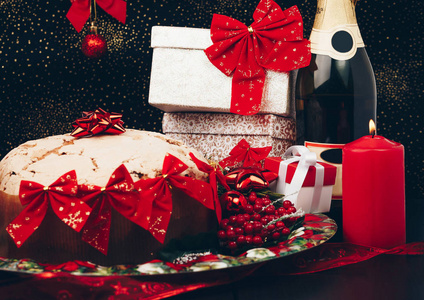 圣诞节或新的一年。在用蜡烛 潘妮托妮和礼品红缎蝴蝶结眼镜香槟