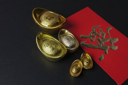 金锭和红包为中国新年喜庆的黑色背景。 汉字意味着幸运和繁荣。 低亮度