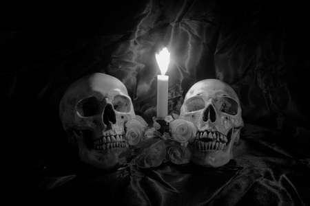 头骨束花和蜡烛的光芒与黑色木制的桌子上，晚上的时间，在黑色和白色背景仍然生活方式
