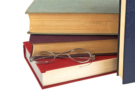 一叠旧书籍和孤立的白色背景上的旧眼镜