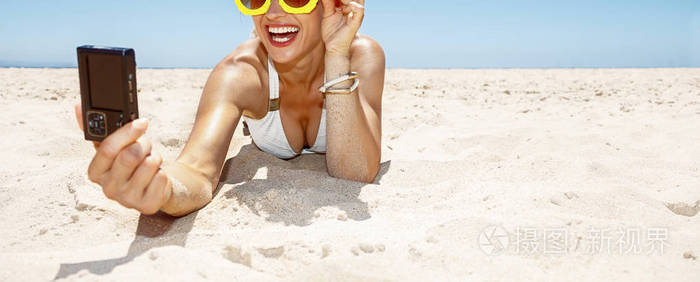 微笑的女士在菠萝眼镜自拍照在沙滩