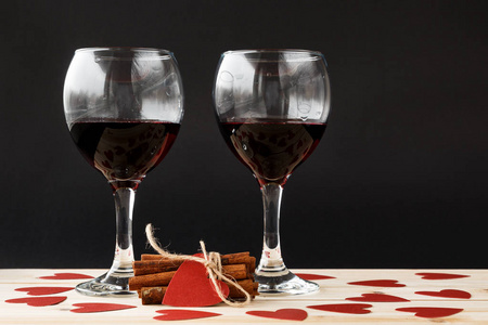 两杯红酒和与周围的红色心系肉桂棒