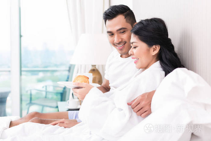 懒洋洋地躺在床上对亚裔夫妇