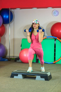 年轻漂亮的白色女孩穿着粉红色运动并与哑铃健身中心体育锻炼