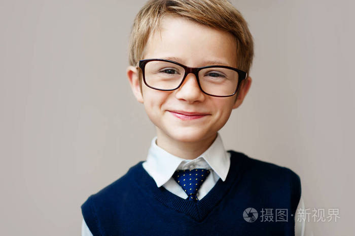 穿着校服的小男孩的特写镜头.快乐男生微笑,看着相机