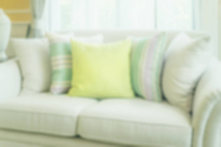 模糊的绿色枕头上现代沙发在客厅里为背景