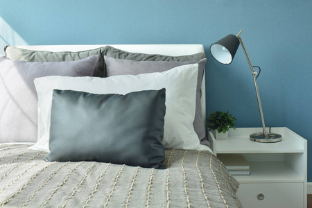 灰 黑灰 白三色枕头在床上与现代风格台灯