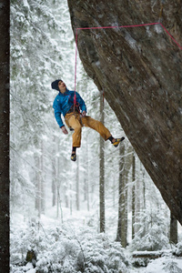 极端的冬季运动。年轻男子攀岩过程中与固定保护绳。爬绳