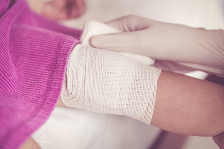 受伤的孩子.儿科医生包扎孩子的膝盖.复古色调照片