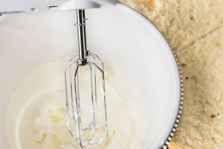 面糊布丁用电动搅拌机,烘烤概念混合面糊奶油蛋糕面团在一个碗里照片