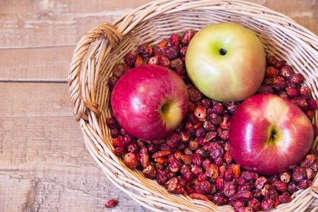 柳条编织的篮子是干玫瑰果和三个苹果