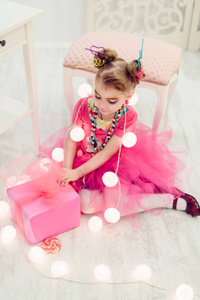 快乐的小女孩穿着粉红色的连衣裙在花环白色内饰糖果