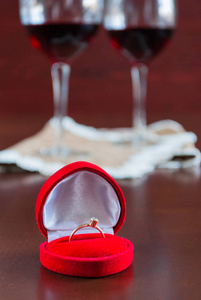 两杯酒木制的桌子上。订婚戒指的红色包装盒