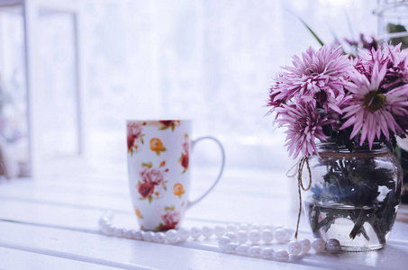 靠窗的粉红色花朵与杯咖啡或茶